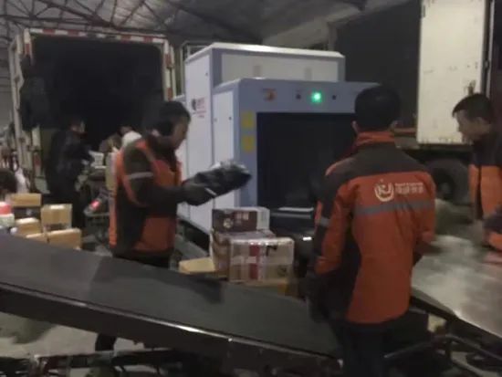 Män skannar paket med röntgenmaskin på ett lager för säker pakethantering.